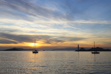 Alone sailboat at sunset. Atmospheric seascape with orange sun