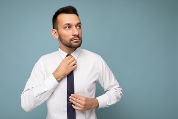 Photo of positive self-confident young handsome brunet unshaven male business man with beard wearing casual white shirt and tie isolated over blue background with copy space for text