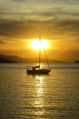 Alone sailboat at sunset. Atmospheric seascape with orange sun