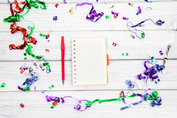 Festivedecorations and notebook with wish list on white rustic table, flat lay style. Planning concept.- Image