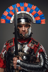 Proud roman soldier with gladius posing against gray background