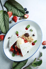 Summer dessert with fresh berries, strawberries, blueberries, biscuit, ice cream and meringue on a white plate on a light gray background. Rustic. Background image, copy space