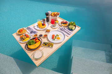 Breakfast in swimming pool floating. Luxury summer vacation or honeymoon destination. Resort hotel gourmet delicious food near the sea with horizon. Beautiful summer breakfast setting, couple travel
