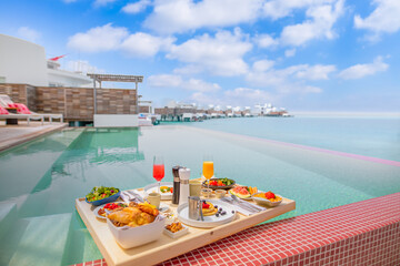 Breakfast in swimming pool floating. Luxury summer vacation or honeymoon destination. Resort hotel gourmet delicious food near the sea with horizon. Beautiful summer breakfast setting, couple travel
