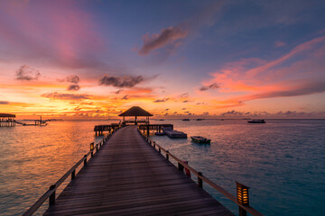 Fototapeta na wymiar Amazing sunset panorama at Maldives. Luxury resort villas seascape with soft led lights under colorful sky. Beautiful twilight sky and colorful clouds. Beautiful beach background for vacation holiday 