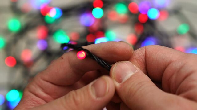 Man attempts to untangle a string of Christmas garland
