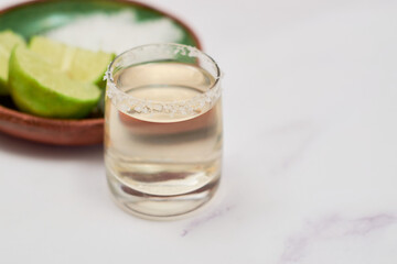 Mexican Gold tequila with lime and salt on marble table.