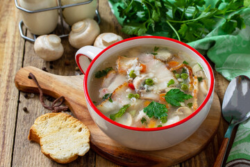 Traditional rustic thick german pea soup with smoked bacon, mushrooms and cereals on wooden table. Hot dinner or lunch.