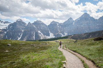 Hiker walking down the path surrounded by mountains in alpine valley, Canadian Rockies, Canada