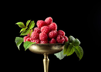 Fresh raspberries with leaves in an old brass dish.