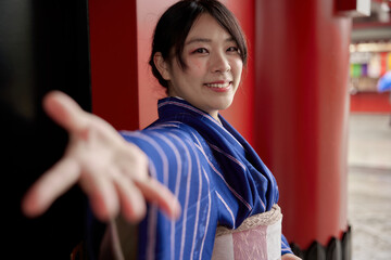 カメラに向かって手を差し出す着物を着た日本人女性