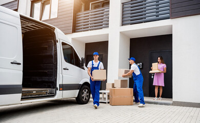 Two removal company workers are loading boxes into a minibus.
