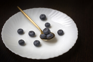 fresh and ripe blueberries on a spoon, a plate with berries