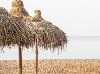 Fototapeta na wymiar Straw umbrellas on empty seaside beach.