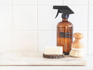 Amber bottle with washing solution, brush and soap on a marble shelf.