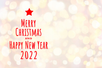 Festive background with blurred golden bokeh lights and text Merry Christmas and Happy New Year 2022 and red star in the left side. Template with copy space for greeting card or holiday invitation.