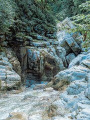 A relief canyon gorge with a collapsed boulder and a river flowing in the middle. Picturesque white cliffs canyon. National preserve