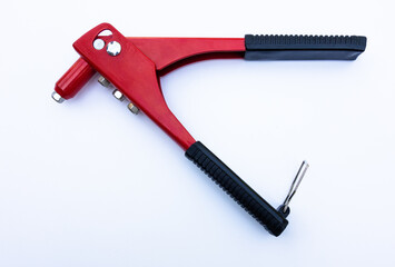 Red metal tool for tightening rivets on white isolate. The riveter is manual. The production tool is red.