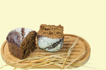 View of cut dark loaf bread and spikelets of rye on a cutting board isolated. Sweden.