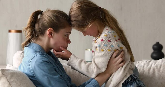 Funny romp. Laughing mother grown elder sister and little schoolgirl tickling messing kidding on cozy sofa. Cute preteen girl having fun with young babysitter play together giggle make funny grimaces