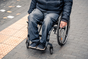 Obraz premium Person with a physical disability waiting for city transport with an accessible ramp.