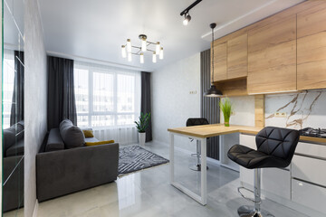 Interior of a modern kitchen, with a bar with wooden inserts and white marble tiles, in a small...