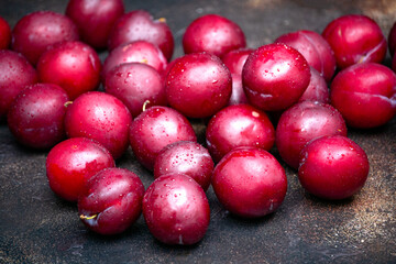 Burgundy plums are scattered on the table in droplets of water.