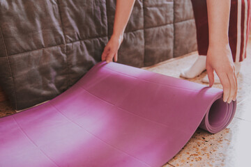 Chica joven extendiendo una esterilla de yoga en el suelo de su dormitorio. Concepto de hacer...