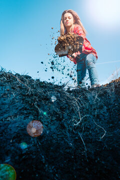 Young Woman Digging A Hole In The Ground With A Shovel