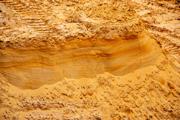Textural sand, with  relief surface, multi-colored layers and different in size of granules, in outdoor sand career, after mining ore and sand for construction.