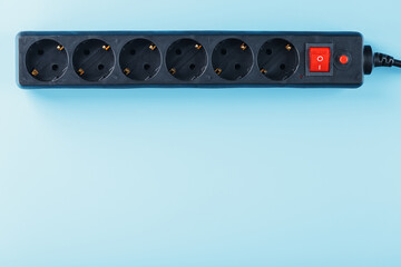 A black surge protector with portable sockets and a red button on a blue background.