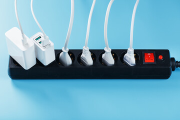 A black mains filter with electrical outlets inserted into it with white plugs of electrical...