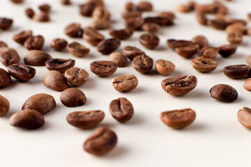 Brown whole coffee grains close-up on light white background, macro photography 