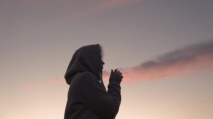 Girl praying on a pink sky background, believe in good good, ask for help, dream looking up, motivation inspiration outdoors, woman thinks meditating, wanderlust concept, heavenly light