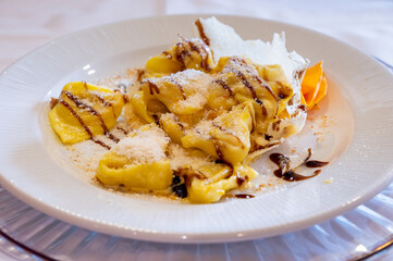 Italian food, fresh home made pumpkin stuffed pasta tortellini or ravioli dumplings with parmesan parmigiano reggiano cheese and Balsamico Vinegar of Modena, Parma, Emilia Romagna, Italy