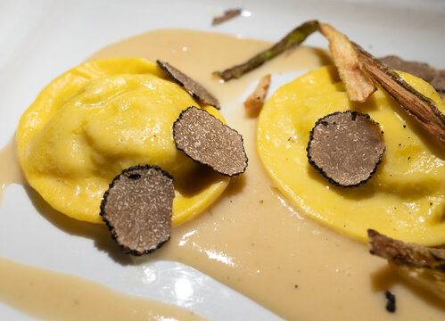 Italian food, fresh home made red potato stuffed pasta tortellacci or ravioli dumplings with summer black truffle and cripsy green asparagus, Parma, Emilia Romagna, Italy