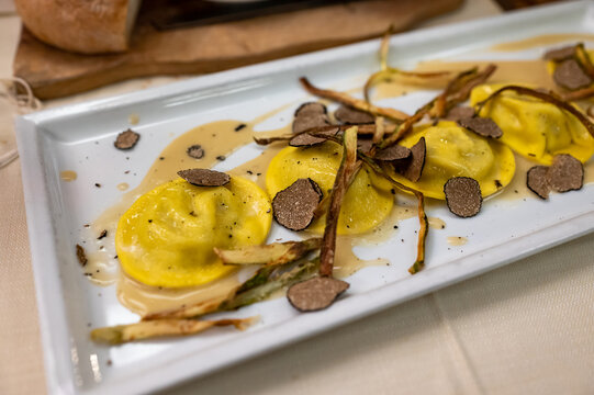 Italian food, fresh home made red potato stuffed pasta tortellacci or ravioli dumplings with summer black truffle and cripsy green asparagus, Parma, Emilia Romagna, Italy