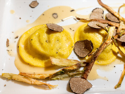 Italian food, fresh home made red potato stuffed pasta tortellacci or ravioli dumplings with summer black truffle and cripsy green asparagus, Parma, Emilia Romagna, Italy