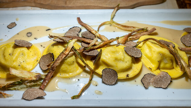 Italian food, fresh home made red potato stuffed pasta tortellacci or ravioli dumplings with summer black truffle and cripsy green asparagus, Parma, Emilia Romagna, Italy
