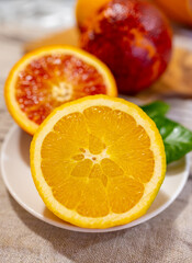 Naklejka na ściany i meble Sicilian sweet juicy yellow and red blood oranges with green leaves close up