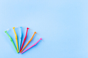 Different size and color interdental brush angles on blue background, horizontal, copy space