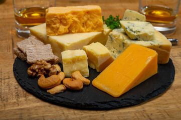 British drinks and food, glasses of Scotch whisky and cheeses collection, blue Stilton, Scottish coloured and English matured cheddar cheeses