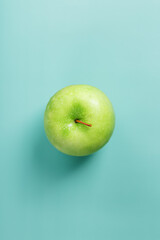 One green apple on a green background with a minimalistic composition.