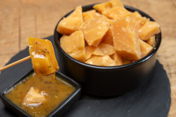 Cheese tasting, small pieces of old Dutch hard cheese and bowl with homemade dill-mustard sauce
