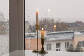 burning candles on background rainy window pane