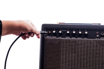 Close up of a hand by connecting the guitar cable to the input jack of the amplifier.