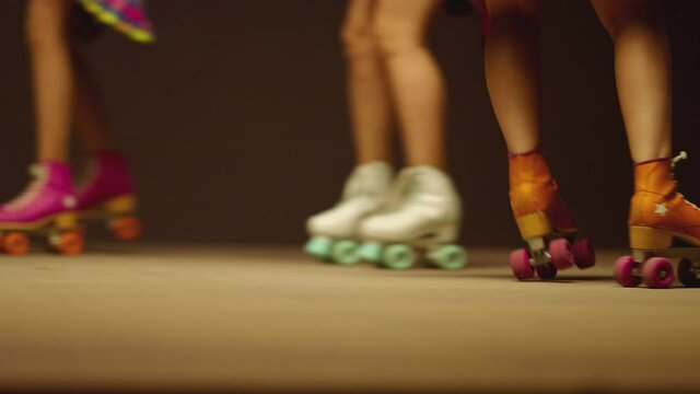 Female legs in roller blades, skating fast at the roller park on floor . Close-up legs of young women is professionally skating . Different kind of and colorful vintage roller blades . Slow Motion