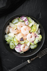 Traditional Waldorf salad with celery, shrimps , with sauce apple and grape, on black stone background, top view flat lay