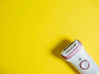 female electric epilator on a yellow background. Copy space, a concept for beauty and personal care devices