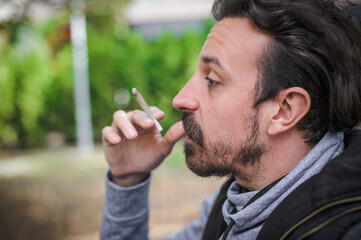 Closeup detail view of man smoke marijuana ganja joint cigarette